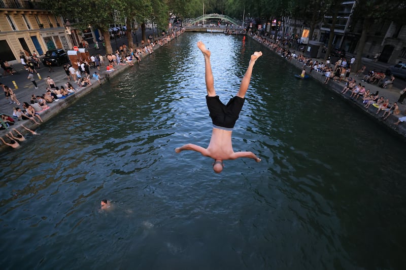 A youth jump from a bridge into the Canal Saint-Martin as France experiences a heatwave. Photograph: Getty Images