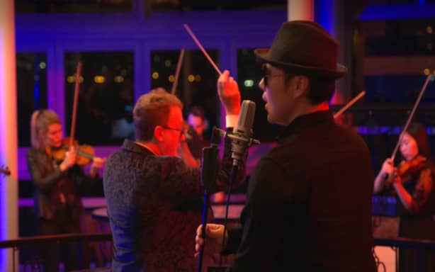 A screenshot from a video of Liu and dozens of paid musicians at a recording session at a wedding venue in Northcote Point, Auckland.