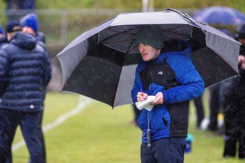 Echo sports writer Barry O’Mahony takes refuge beneath an umbrella as torrential rain falls in Rosscarbery. Picture: Chani Anderson