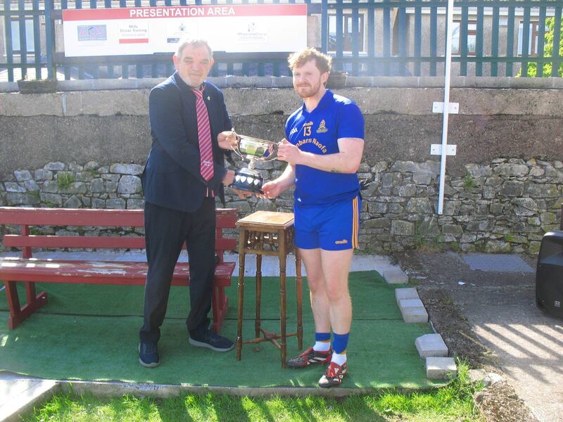 Seandún Chairman Mick Buckley presents the trophy to St Finbarr's Ruairí O'Connor