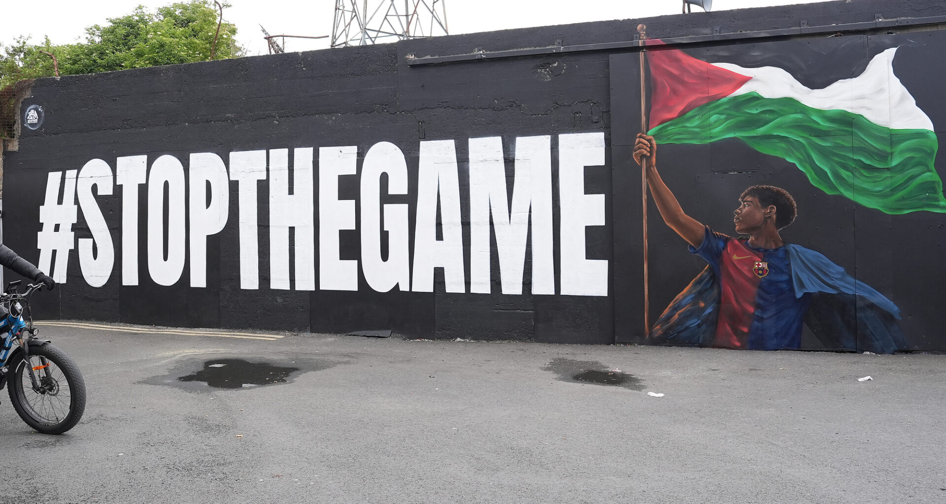 A Deliveroo rider passes the new Lamine Yamal mural outside Bohemians' Dalymount Park, which features the Barcelona star with a Palestinian flag and the words "stop the game", referencing calls to halt the Ireland v Israel European cup fixture. Picture: PA