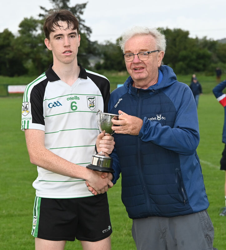 Aidan Lutrell, Rebel Óg presents the trophy to Douglas captain Emmett Cronin after defeating Nemo Rangers in the Rebel Óg under 16 Premier 1 football league final at Shanbally. 
