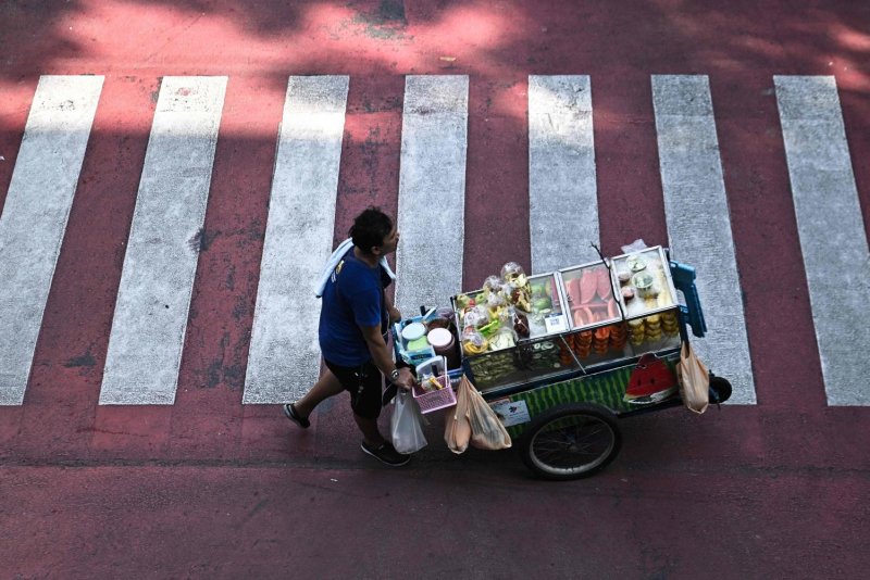 A street vendor pushes a cart of fresh fruit along a road in Bangkok. The new co-payment scheme is expected to support small businesses. (Photo: AFP)