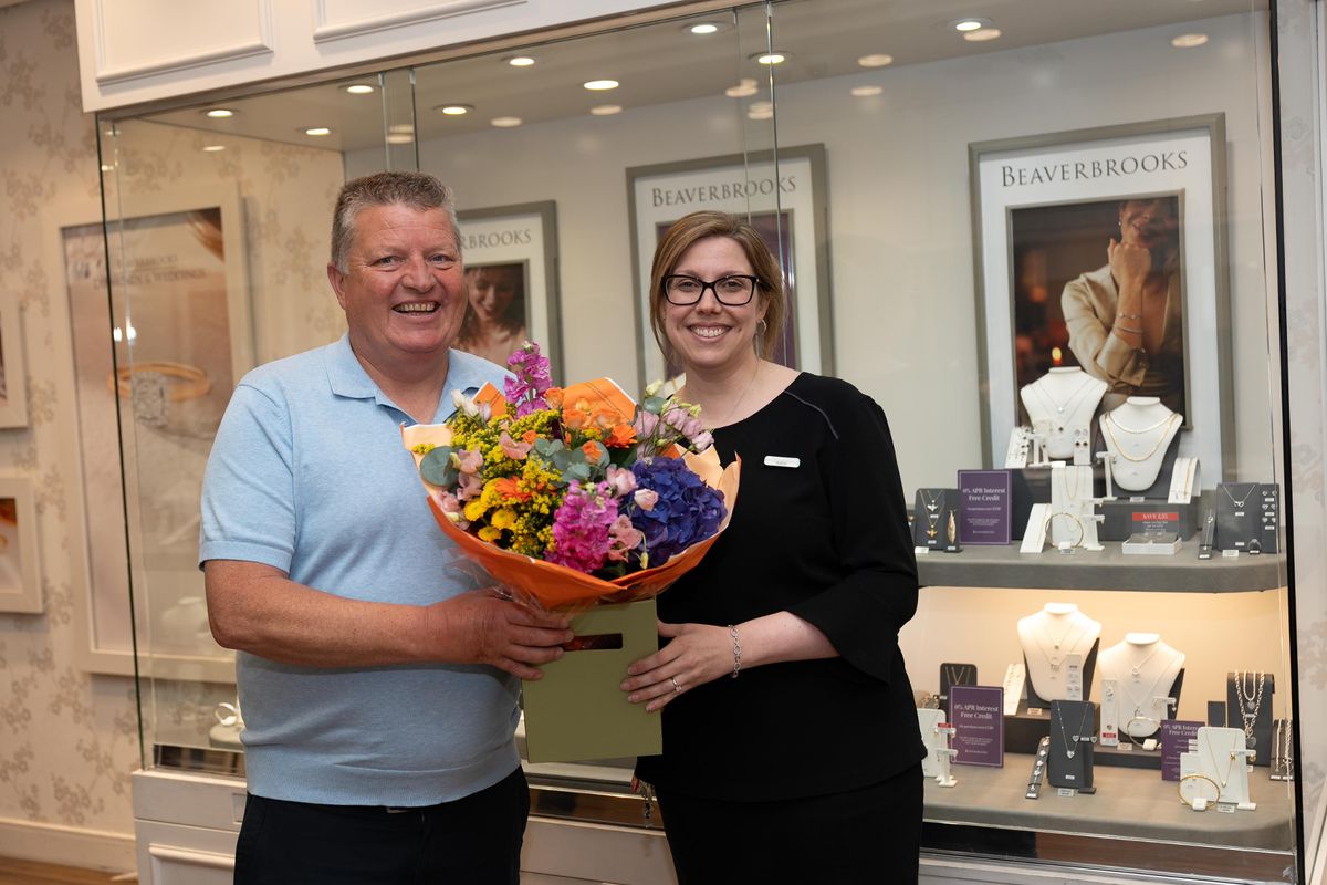 Gary MacDonald, who quit his job after scooping £5.2 million on the lottery, with Katie Feeney, during his visit to his former workplace to surprise old colleagues with flower bouquets and Lotto lucky dip tickets.