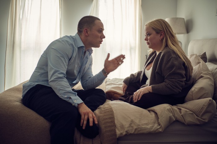I Am Helen - Me and You Productions Nicola Coughlan and Joe Cole in I Am Helen, sat on a bed facing each other. He is holding his hand out gesturing at her, as if in an argument.