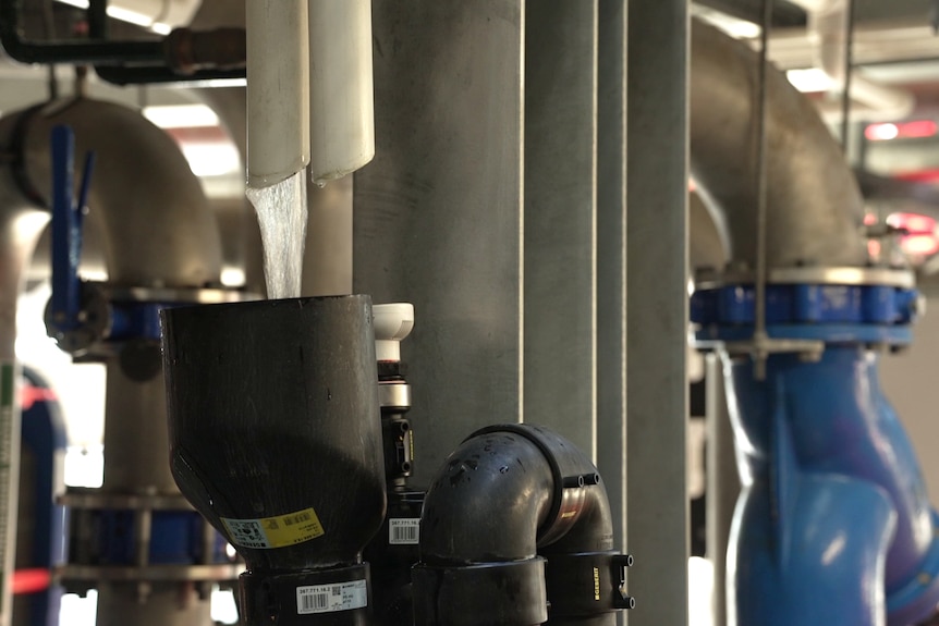 Water runs through a small PVC pipe into a catchment inside a large evaporative cooling system in a data centre.