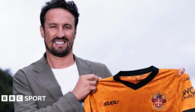 Cesar Peixoto holding a Wolves shirt while smiling