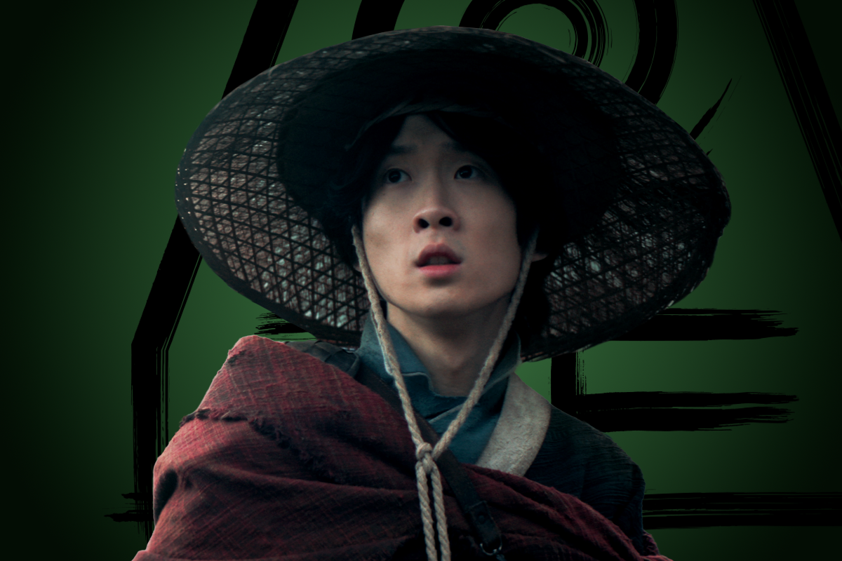 Nathaniel Kong as Longshot in traditional East Asian clothing and a wide-brimmed woven hat, wrapped in a maroon shawl, looks up with a serious expression against a dark green background with abstract black lines.