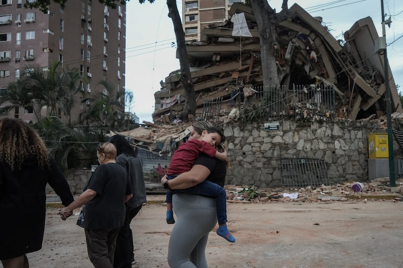 People walk past a collapsed building following an earthquake in Caracas. Photograph: Manaure Quintero/AFP/Getty Images