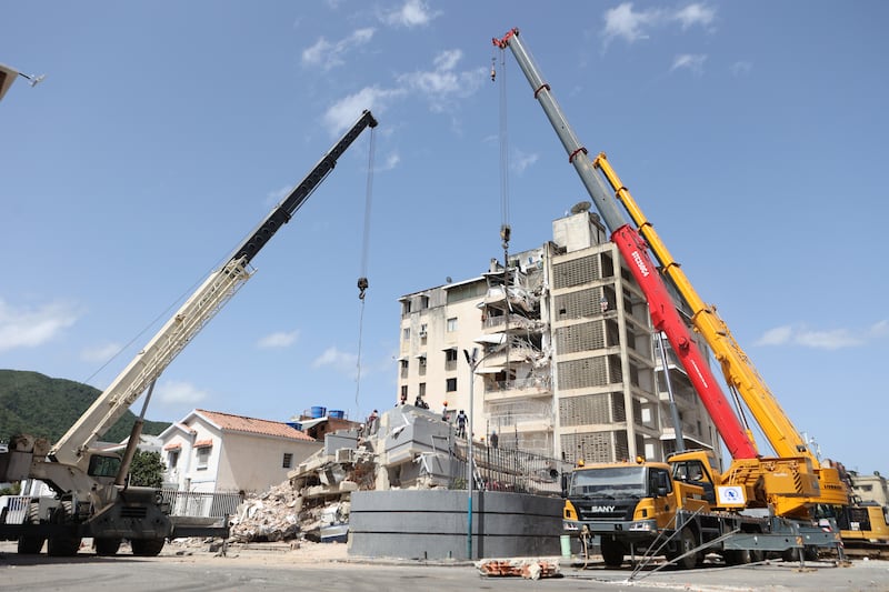 Cranes remove debris from a collapsed building. Photograph: Pedro Mattey/AP