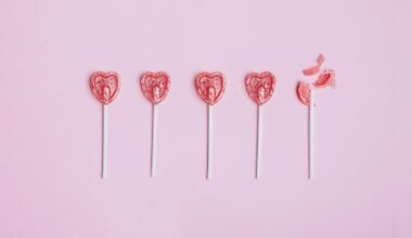 Five lollipop hearts on a pink floor, but the last one is smashed to pieces.