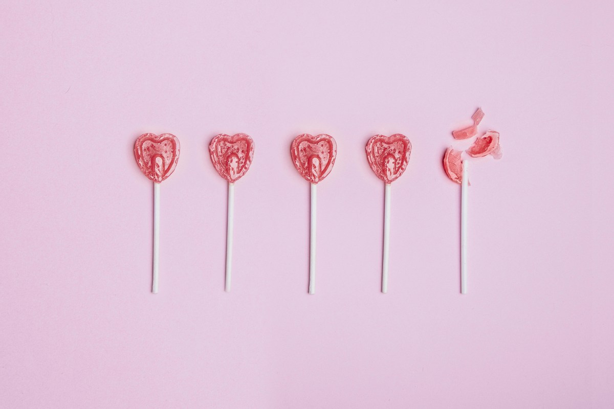 Five lollipop hearts on a pink floor, but the last one is smashed to pieces.