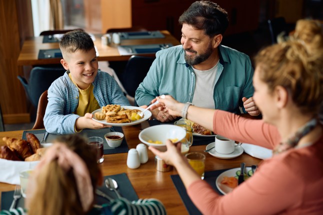 Happy boy enjoying in breakfast with his family in a hotel restaurant.