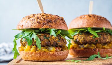 Vegan lentil burger with arugula, mustard sauce, fresh vegetables and sweet potato fries on a wooden board. Vegan food concept.