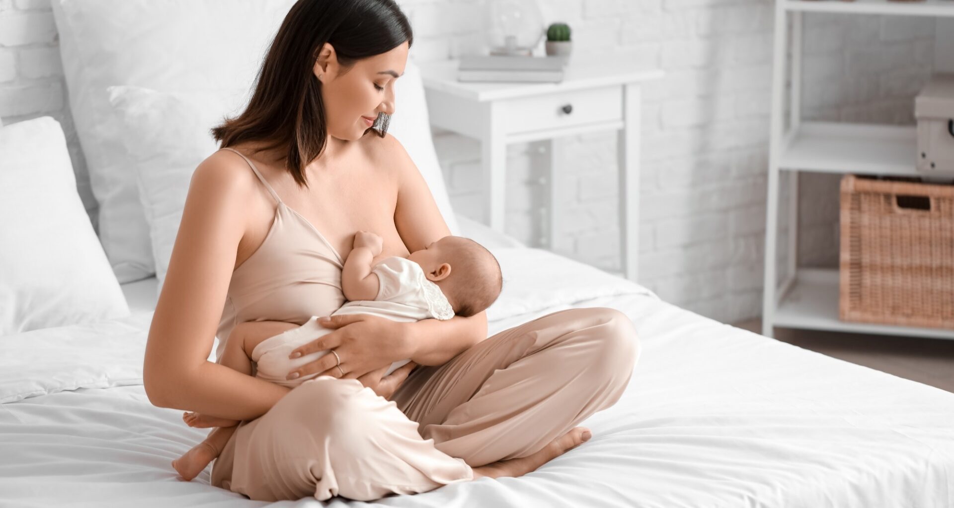 Young woman breastfeeding her baby in bedroom