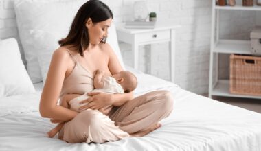 Young woman breastfeeding her baby in bedroom