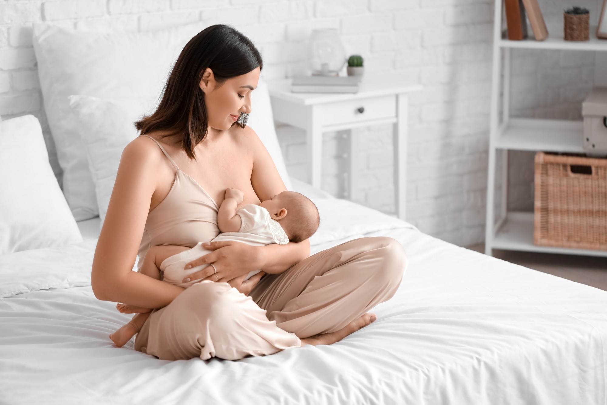 Young woman breastfeeding her baby in bedroom