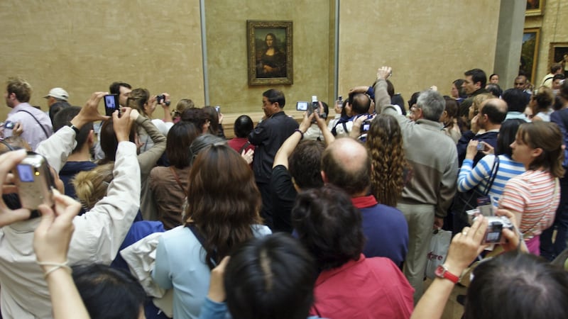 Crowds of tourists attempt to take photographs of the Mona Lisa at the Louvre museum in Paris.