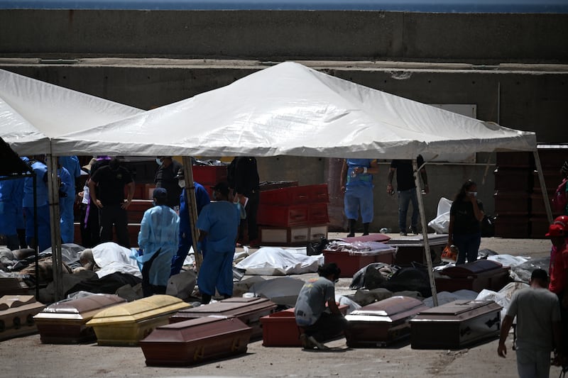 Forensic experts stand amid victims and coffins in La Guaira, Venezuela, on Monday. Photograph: Juan Barreto/AFP via Getty
