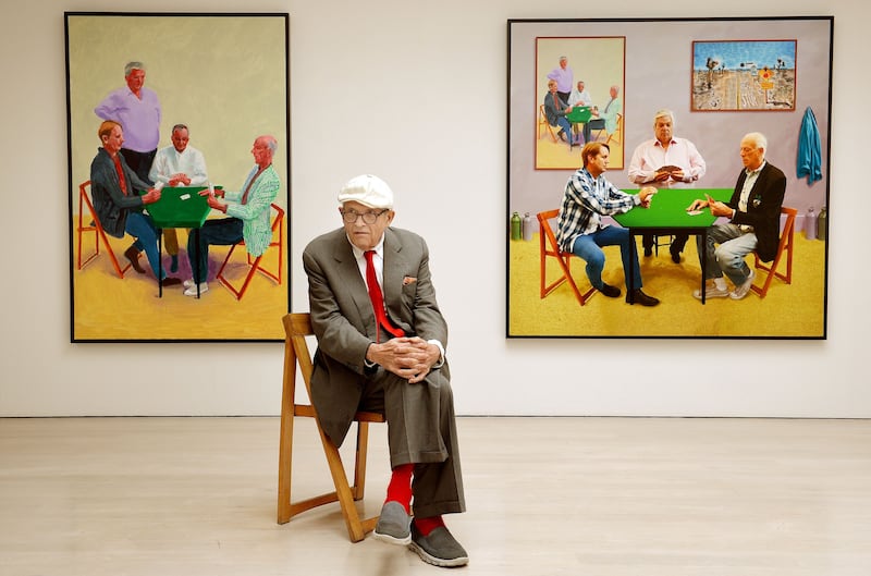 David Hockney sitting in front of his work entitled Card Players (left) and A Bigger Card Players. Photo: John Stillwell/PA