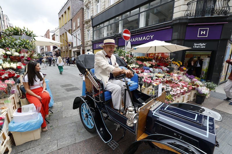 Jim Kiernan in his 122-year-old motor car and flower trader Olivia Cleary near Davy Byrne's pub on Dublin's Duke Street on Tuesday. Photograph: Nick Bradshaw/ The Irish Times