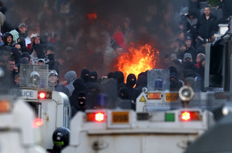 Masked protesters stand at a police blockade, keeping them from reaching a hotel previously believed to house migrants, in Glengormley, north of Belfast. Photograoh: Henry Nicholls/AFP via Getty Images