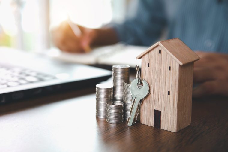 Wooden house with coins stack in graph shape for real estate or money savings planning and bank home loan or financial investment insurance.