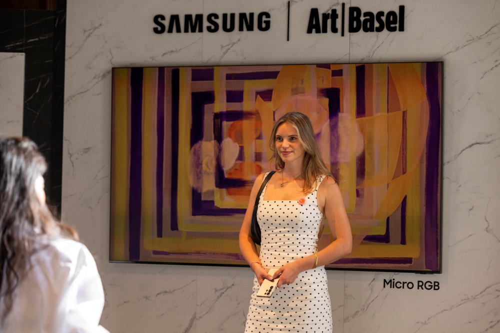 ▲ A guest poses in front of Micro RGB as it displays artwork by Athene Galiciadis from the Art Basel in Basel 2026 