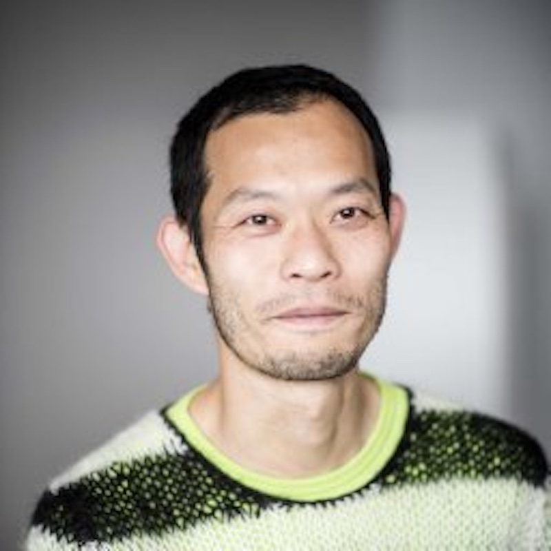 Smiling young man with short black hair wearing a sweater.