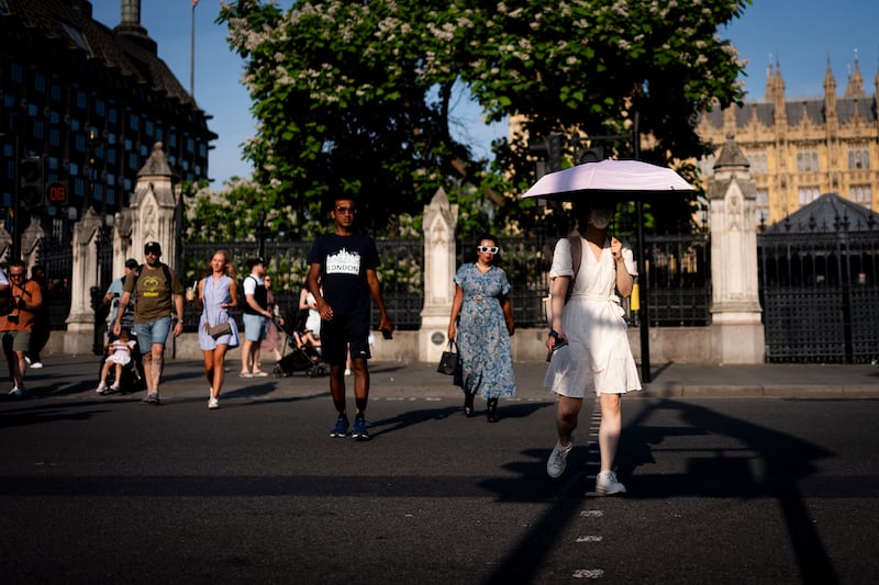 People shelter from the sun at Parliament Square, central London. Photograph: Jordan Pettitt/PA Wire
