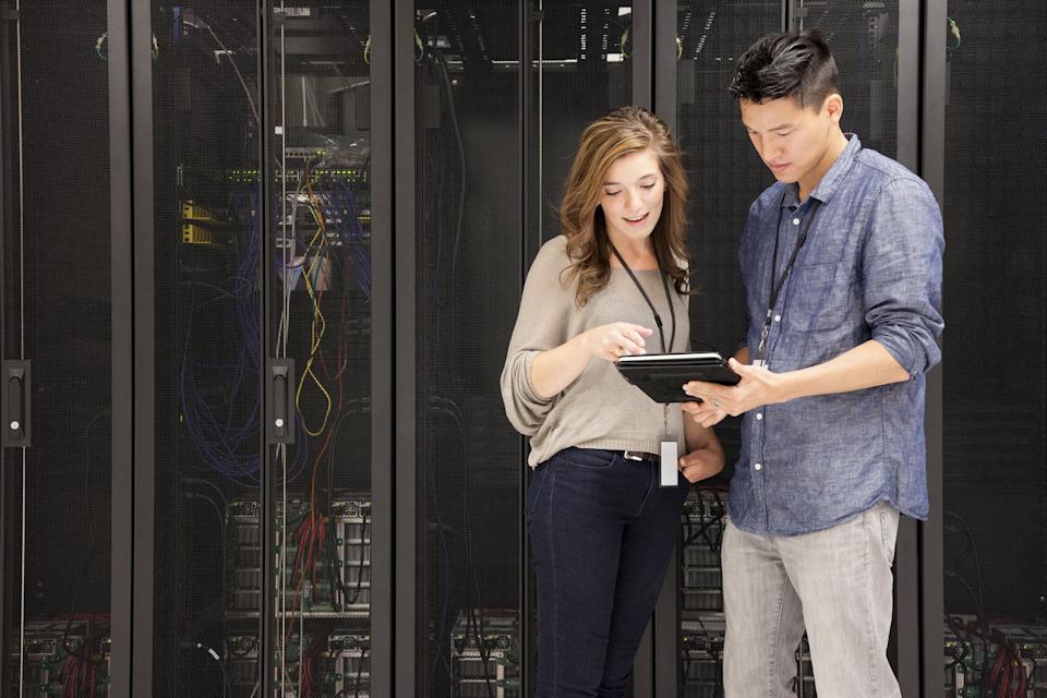 People viewing a mobile device in front of stacks of supercomputers.