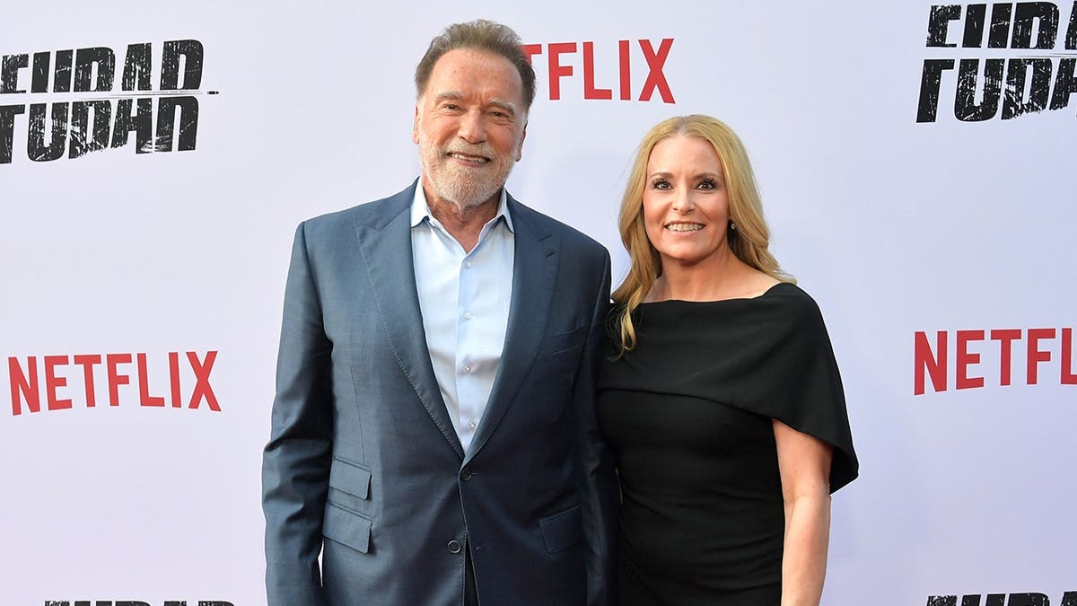 Arnold Schwarzenegger and Heather Milligan standing at Netflix Tudum Theater in Los Angeles