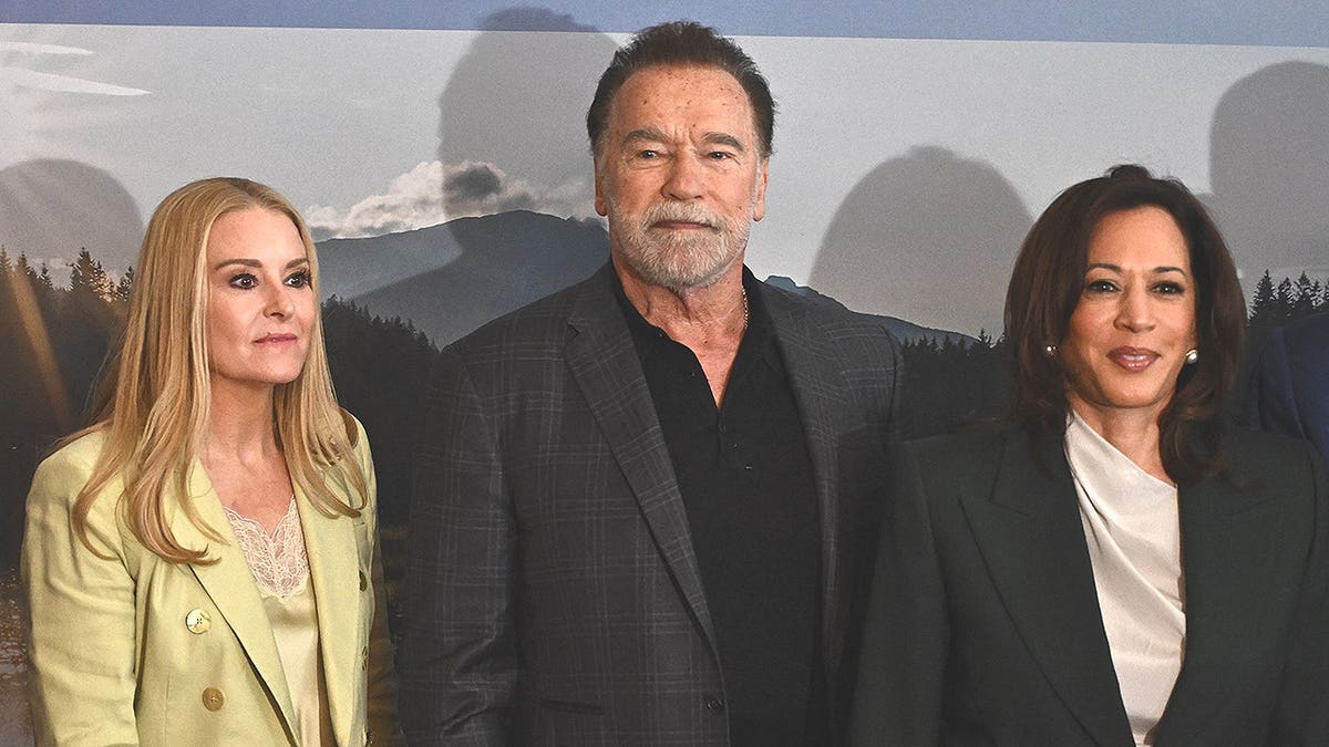 Arnold Schwarzenegger, Heather Milligan, and Kamala Harris posing together at an event in Vienna
