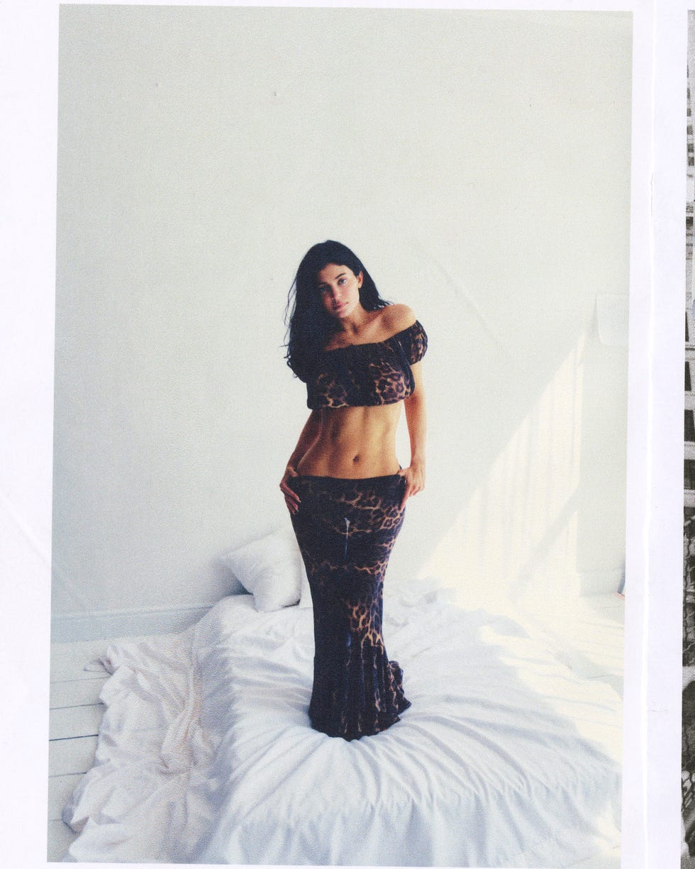 Woman in leopard print outfit standing on a bed in a bright room. Woman in leopard print outfit standing on a bed in a bright room.
