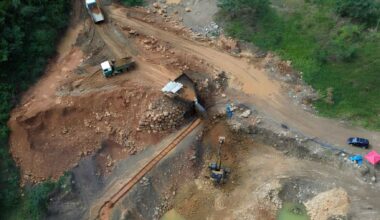 Aerial view of gold mining dredges operating in a muddy Amazon river in Bolivia, showing sediment pollution.