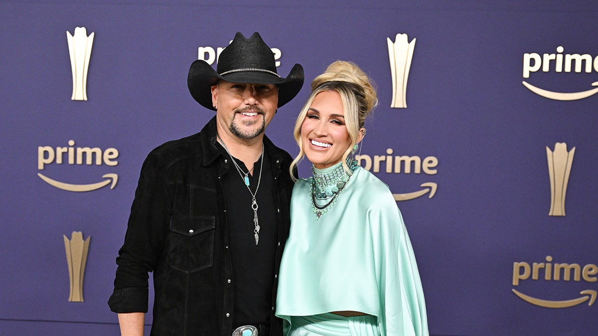 Jason Aldean and Brittany Aldean standing together at the 59th Academy of Country Music Awards in Frisco, Texas.