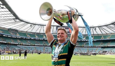 Northampton flanker Henry Pollock, wearing the club's yellow, green and black shirt, lifts the Prem Rugby trophy above his head
