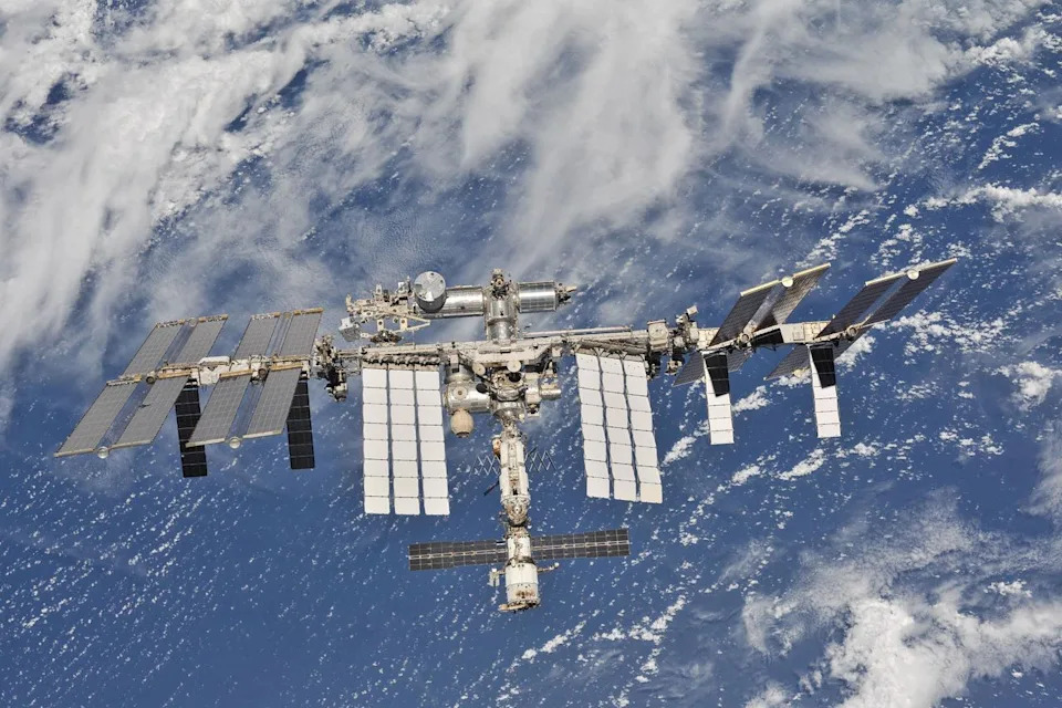The international space station can be seen in the foreground with the blue and white of Earth behind it.