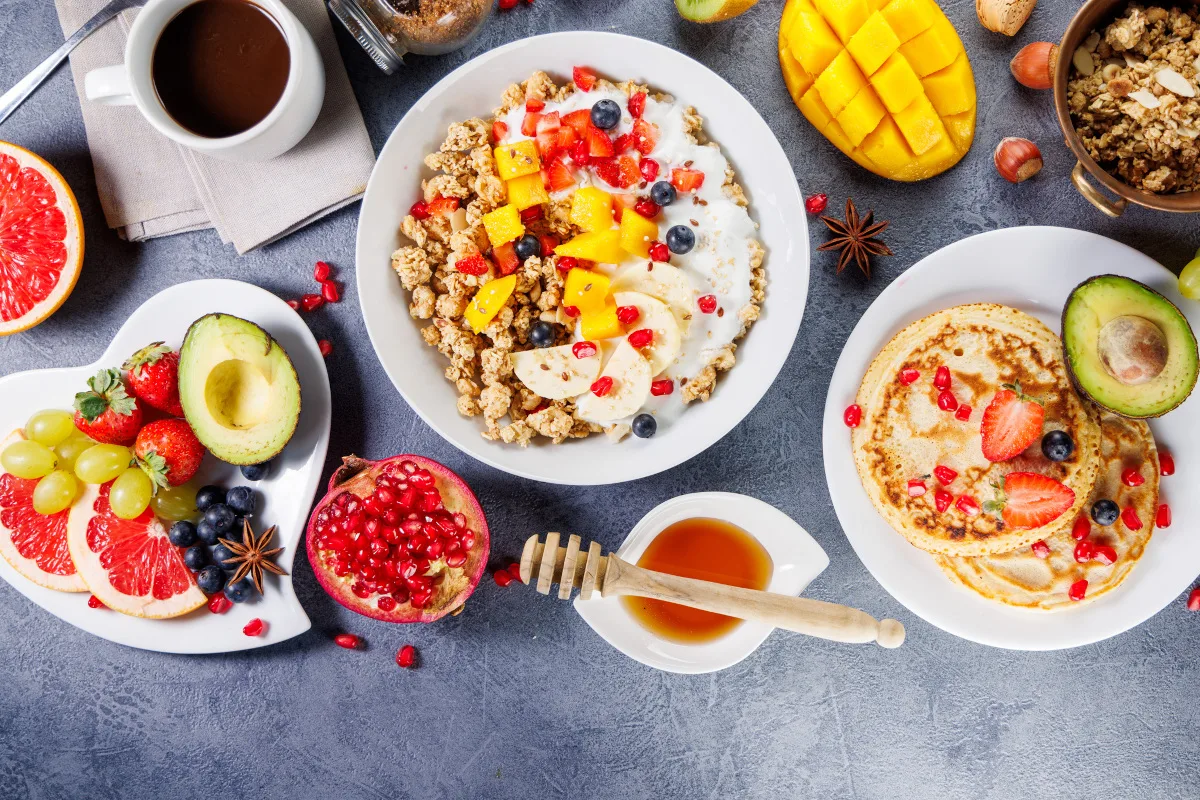 healthy breakfast with granola, pancakes, fresh fruits and coffee cup, top view