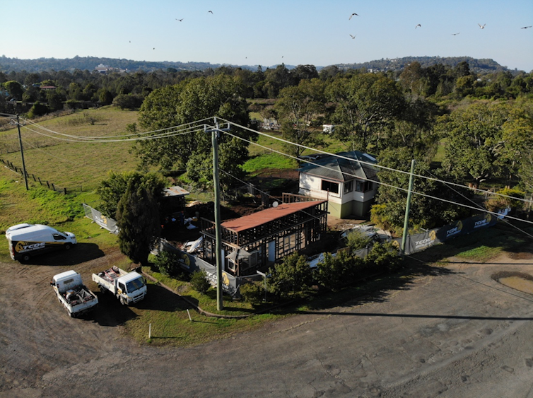 An aerial photo of two houses on a green hill.