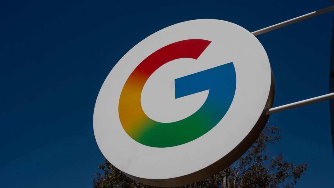 A large sign with Google's "G" logo hangs outside during the daytime.