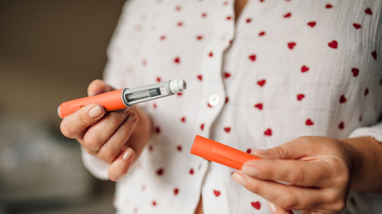 Female holding a GLP-1 pen in front of her