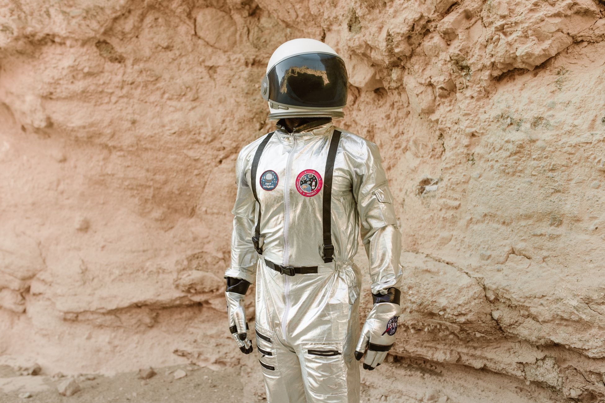Astronaut in a shiny silver space suit standing on rocky terrain, showcasing space exploration imagery.