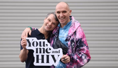 Irish HIV/AIDS activists Robbie Lawlor and Veda Lady pose for a photo, holding a sign reading
