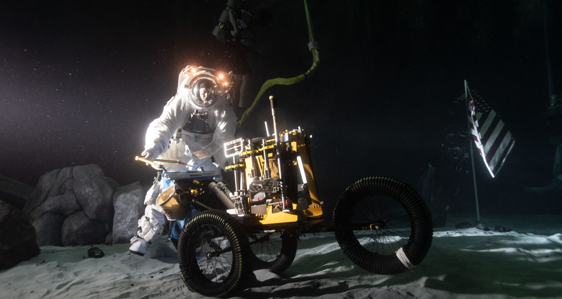 Wearing a spacesuit, Scott Wray conducts an underwater test in lunar night-like lighting at the bottom of the Neutral Buoyancy Laboratory pool.