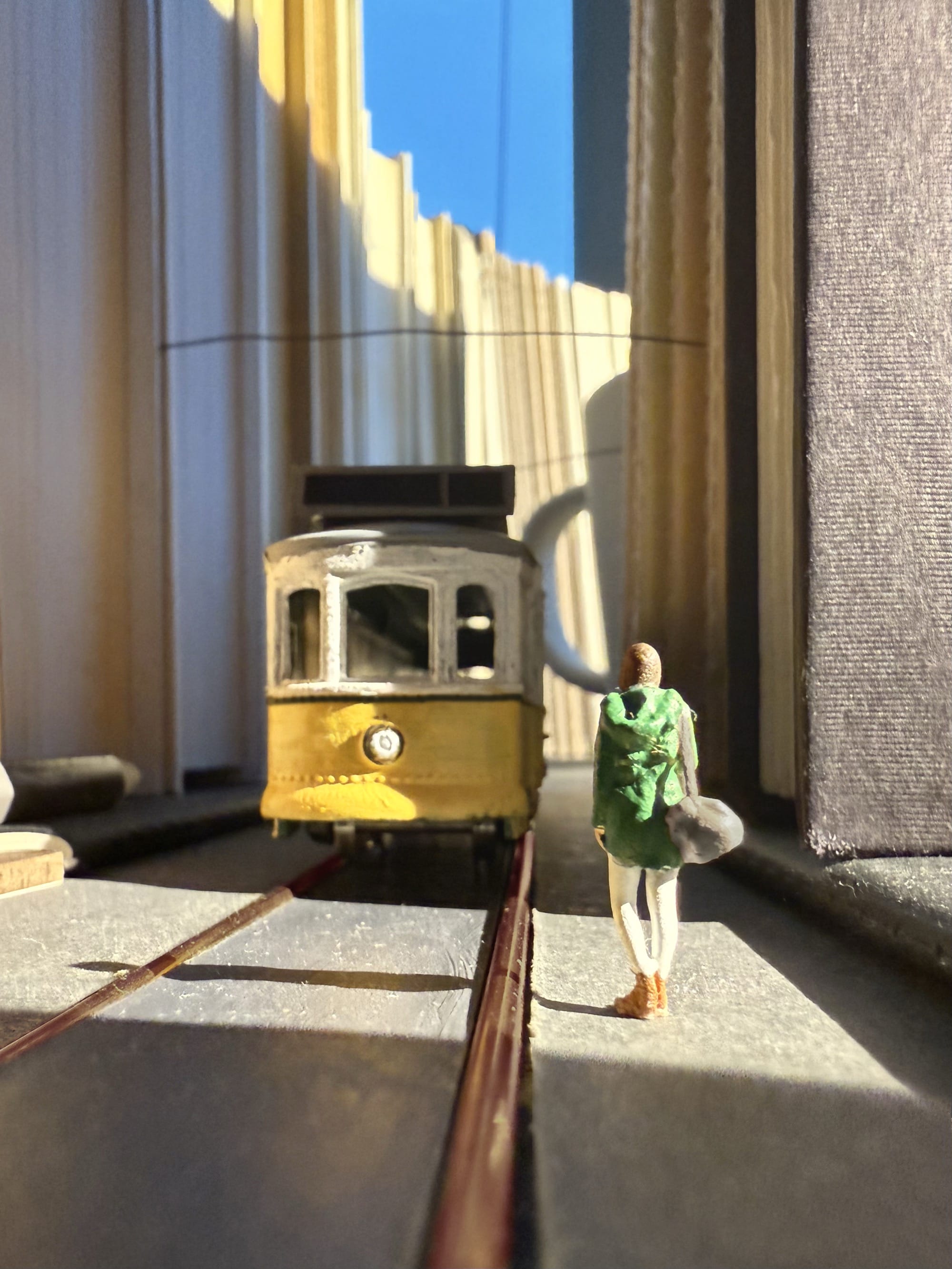 a photograph of a miniature tableau by Derrick Lin of a woman standing in a city made of books, waiting for a tram to arrive