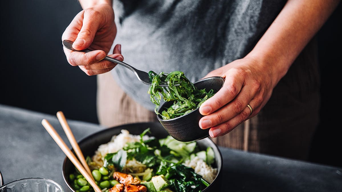 Woman eating a bowl of omega 3 rich salad with salmon and vegetables.