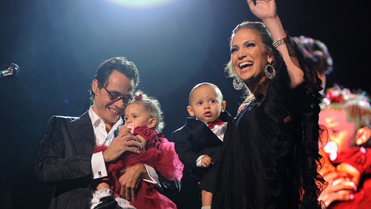 Marc Anthony and Jennifer Lopez standing on stage with their twins Max and Emme at Madison Square Garden.