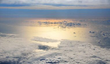 Aerial view of marine clouds over the ocean reflecting sunlight, with bright light reaching the water surface below.