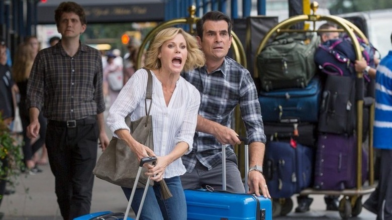 Julie Bowen as Claire Dunphy and Ty Burrell as Phil Dunphy, walking through New York with suitcases in Modern Family.